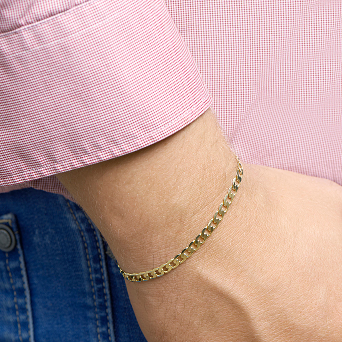 Gouden gourmet armband: model draagt de 14 karaat geelgouden 6-zijdig geslepen gourmette armband van 4,8 mm breed, lengte 20 cm