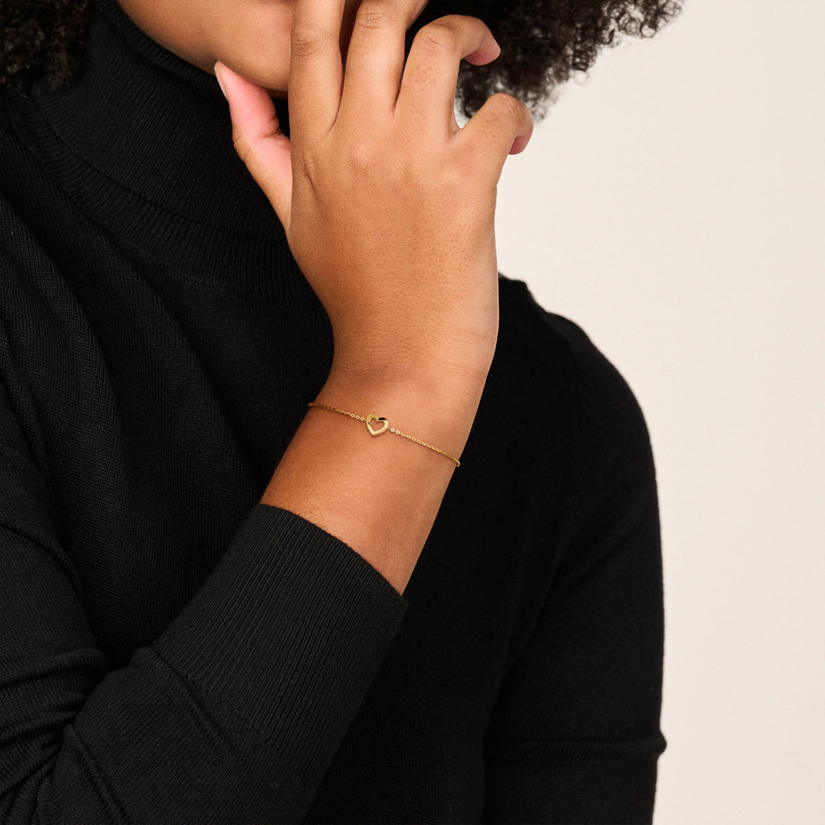 Model draagt de 14 karaat geelgouden armband met open hartje om de pols.