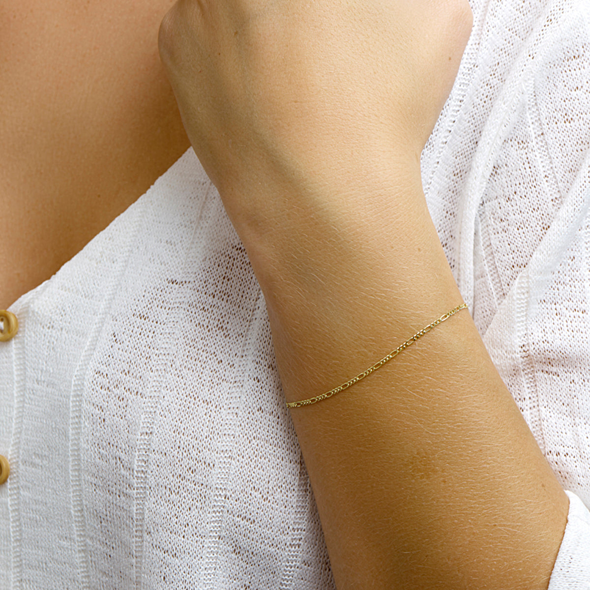 Gouden figaro armband: model draagt de 14 karaat geelgouden figaro armband van 1,5 mm breed, lengte 18 cm