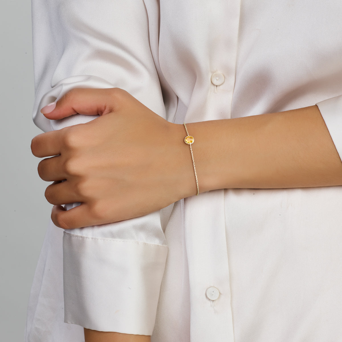 Model draagt de gouden ankerarmband met citrien van 14 karaat om de pols.