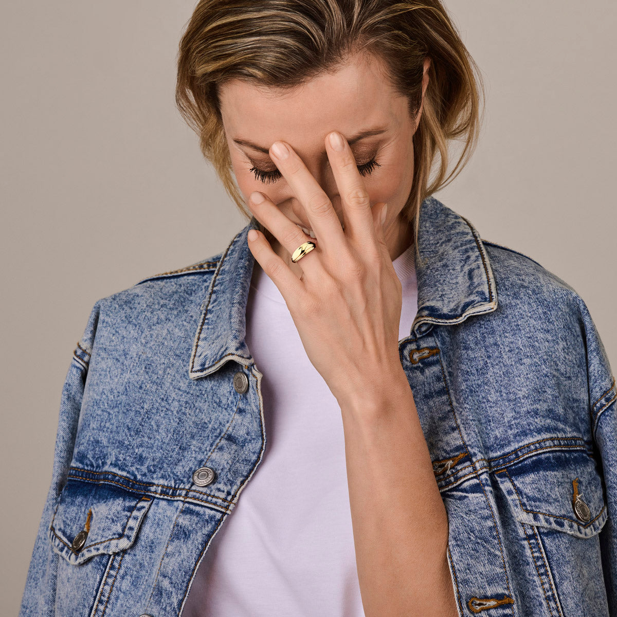 Model draagt de gouden brede ring van 14 karaat aan de hand.