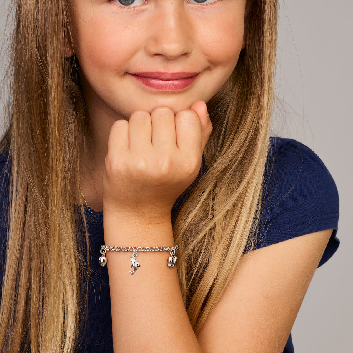 Model draagt de zilveren kinderarmband met bedels om de pols.
