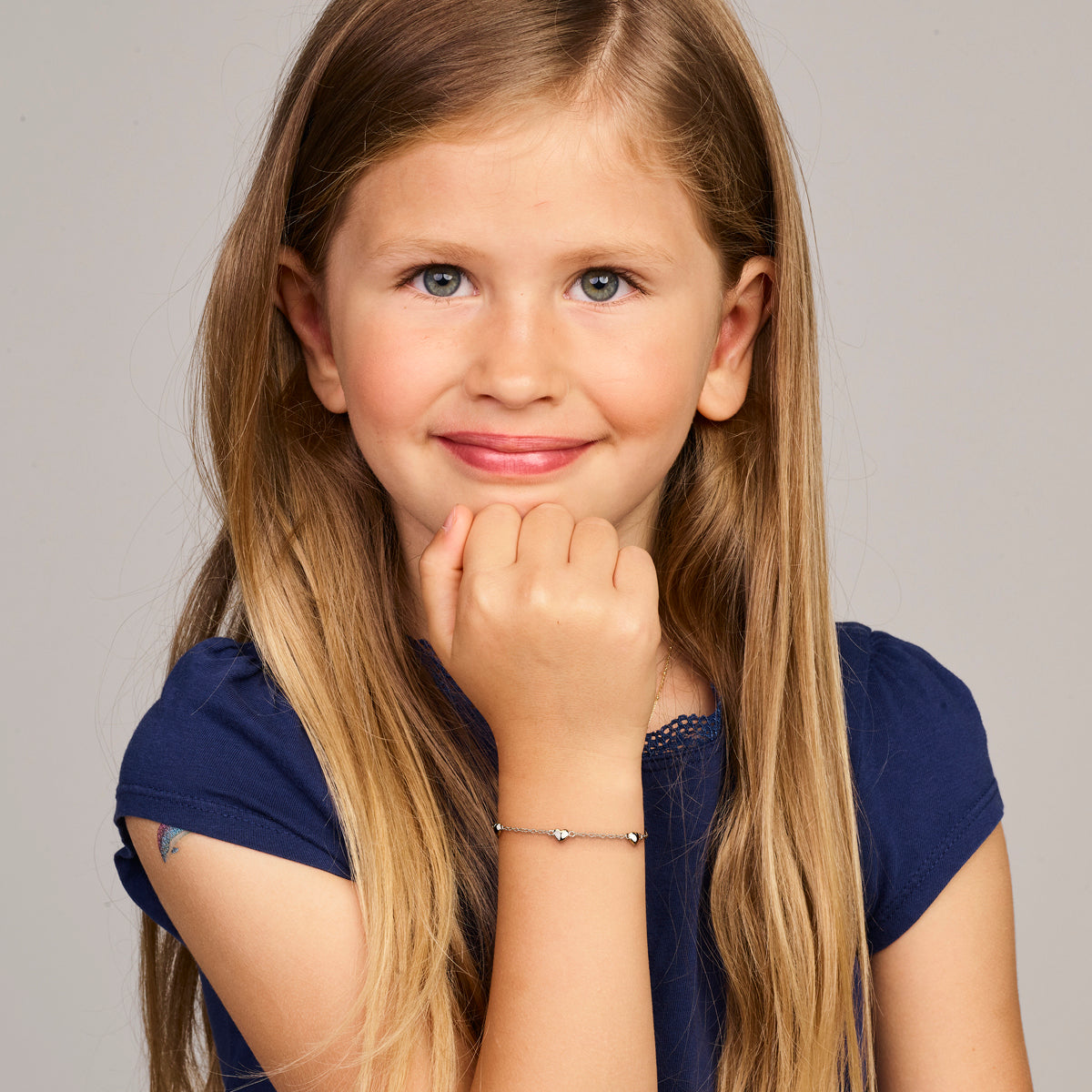 Model draagt de zilveren kinderarmband met hartjes om de pols.