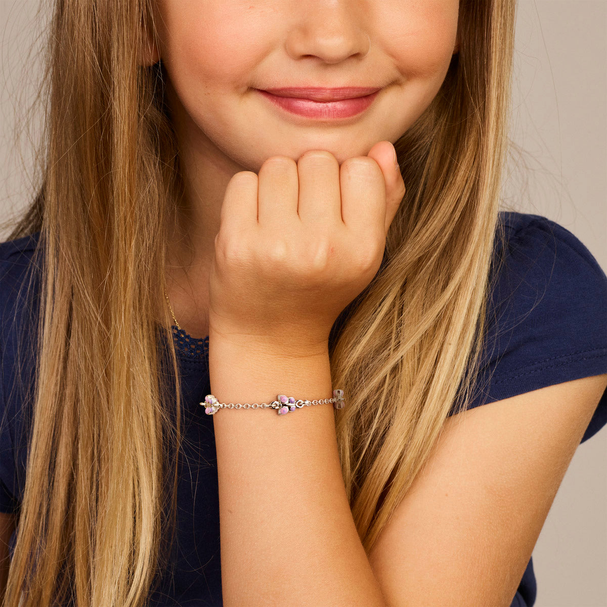 Model draagt de zilveren kinderarmband met paarse vlinders om de pols.