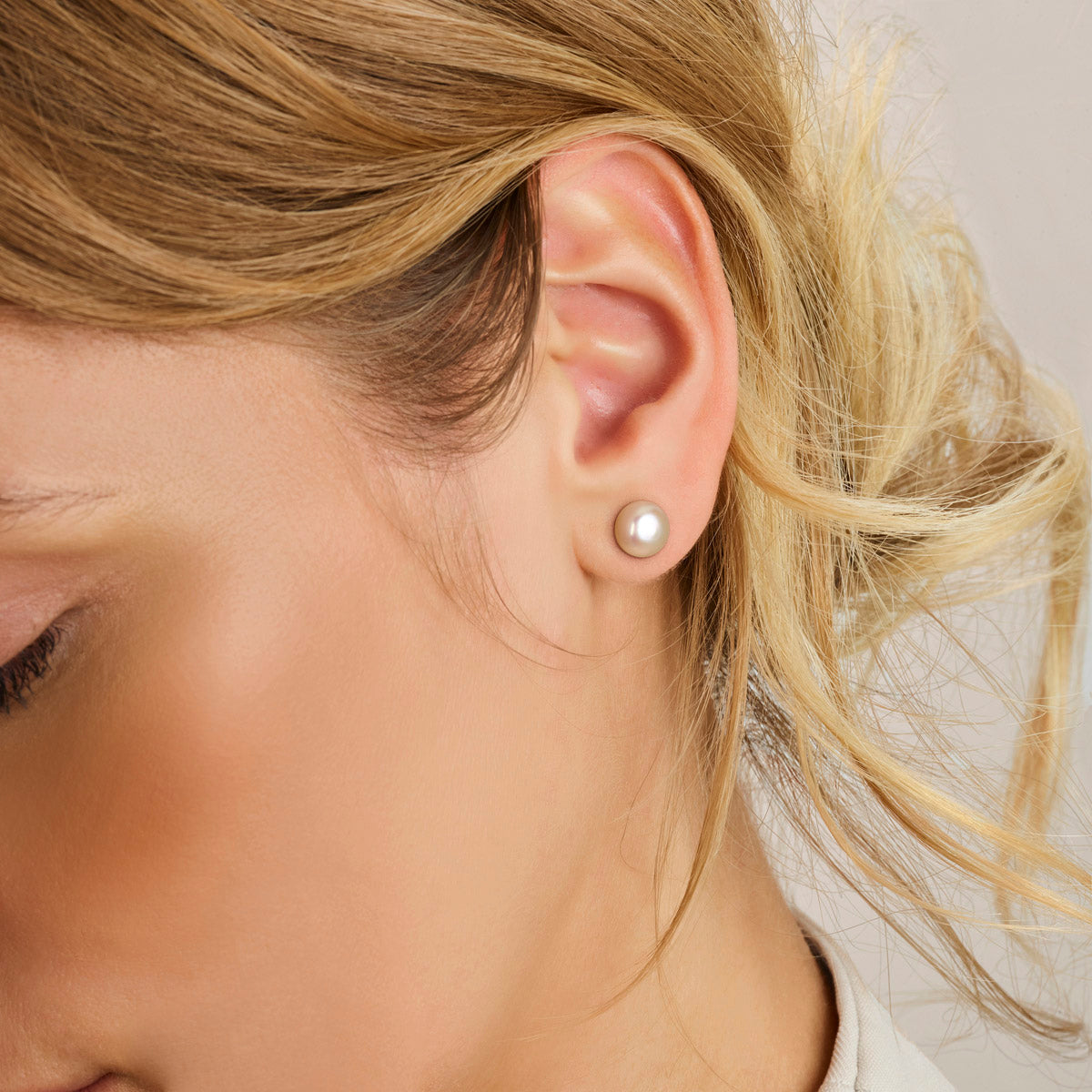 Model draagt de zilveren oorknopjes met parel in het oor.