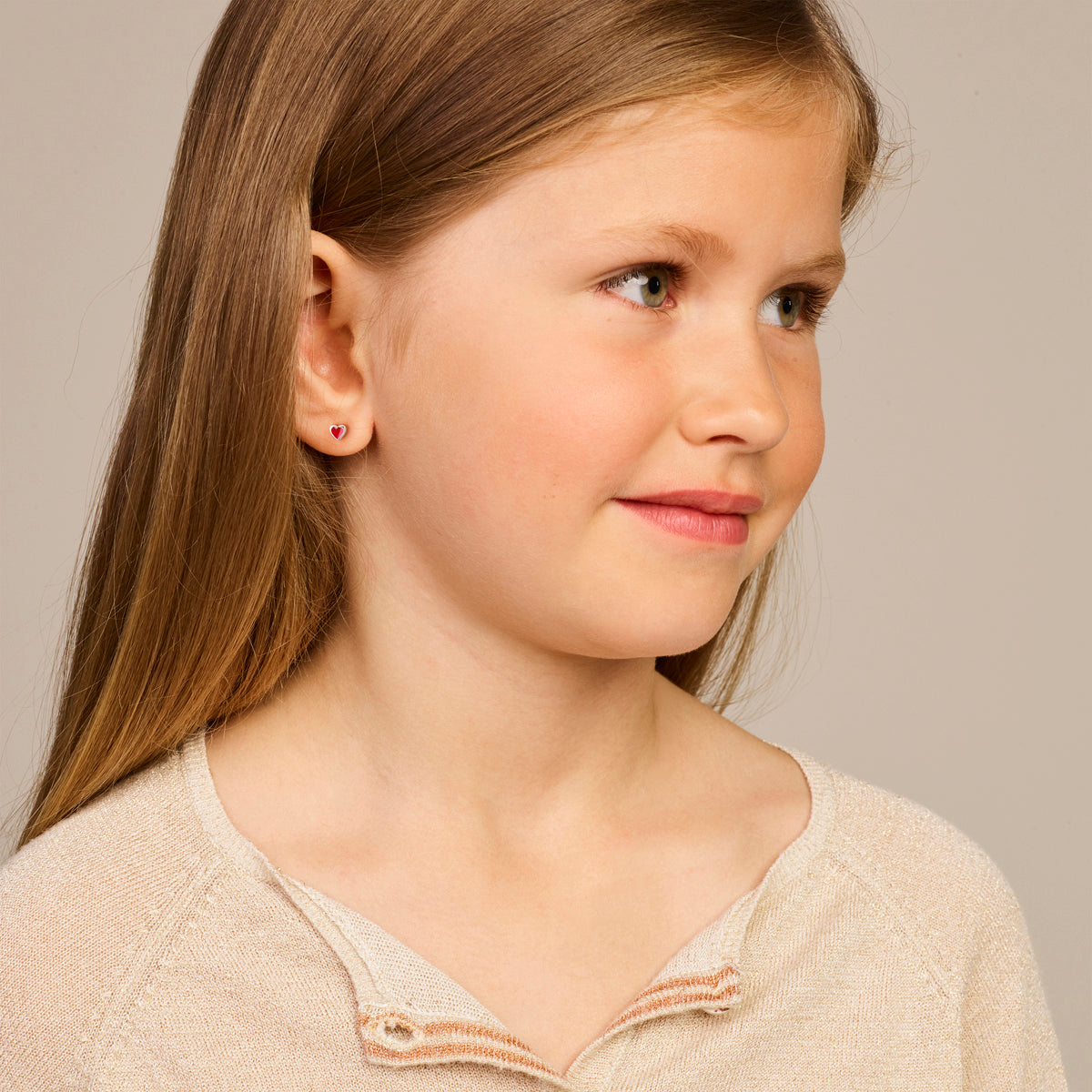 Sfeerfoto van de rode 'Cara' oorknopjes op het oor van een kind.