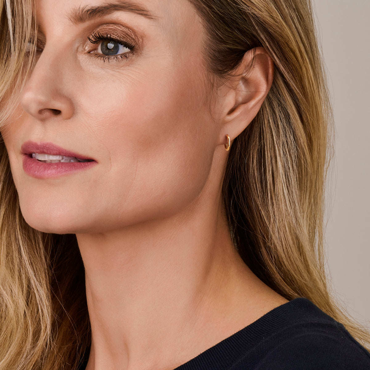 Een model draagt de 13 mm 'Sophie' oorringen, waarbij te zien is dat ze subtiel en klein om de oorlel vallen.