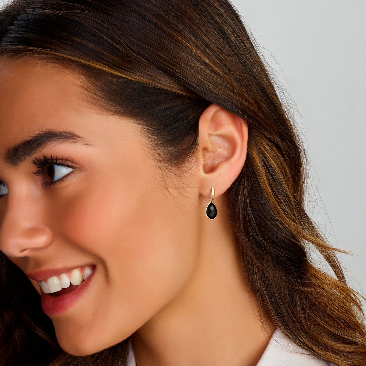 Een model draagt de gouden 'Gioia' oorbellen met zwarte steentjes die krachtig en elegant glanzen.