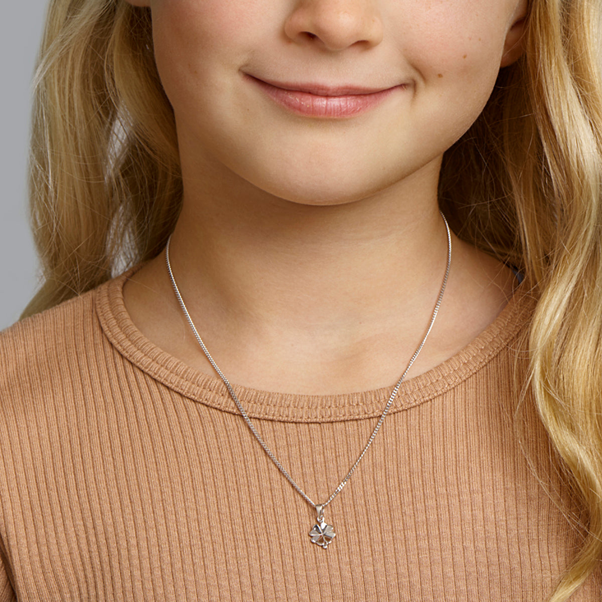 Een kind model draagt de zilveren 'Feli' gelukshanger om de grootte te tonen.