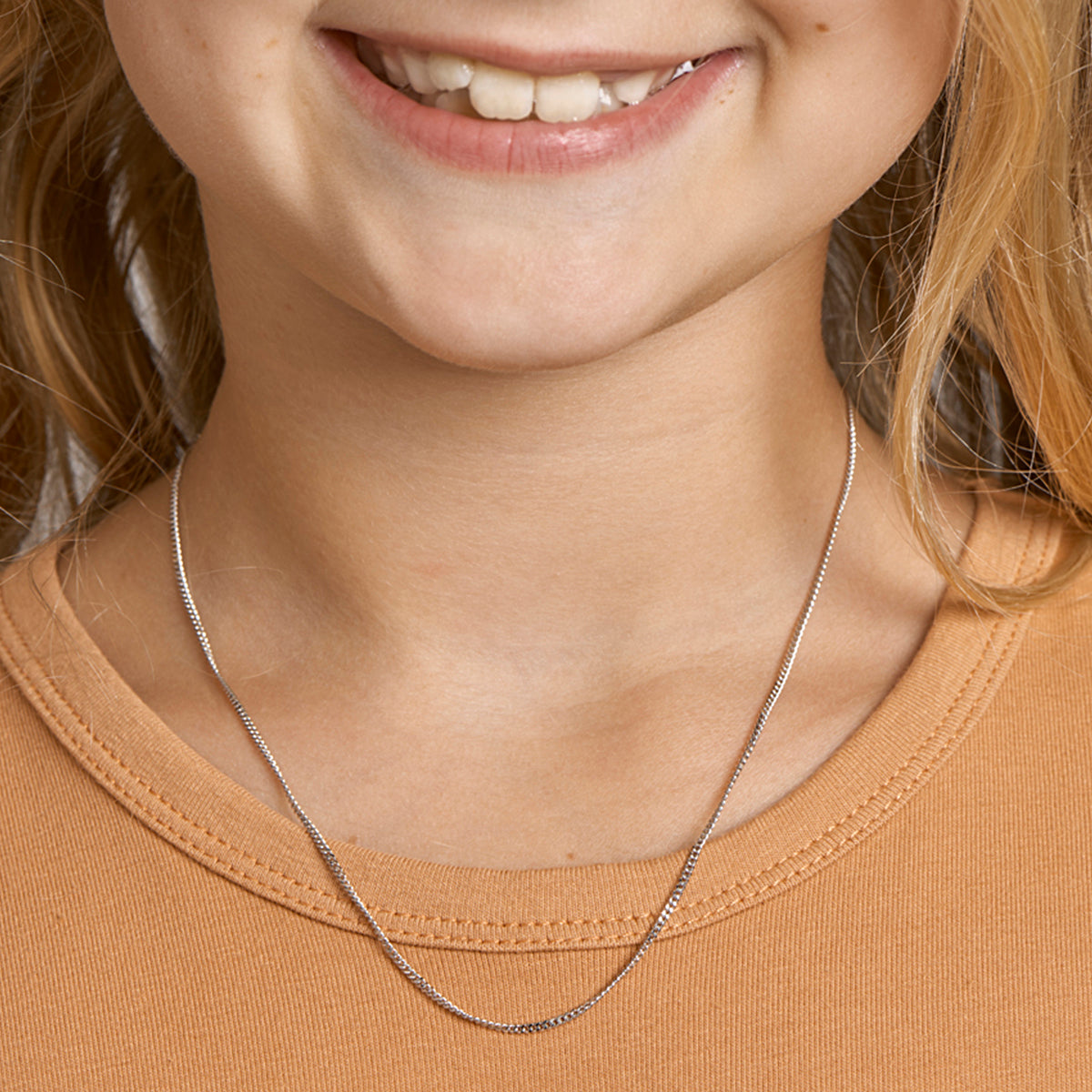 Een jong model draagt de zilveren basis ketting op de kortste stand in de hals.