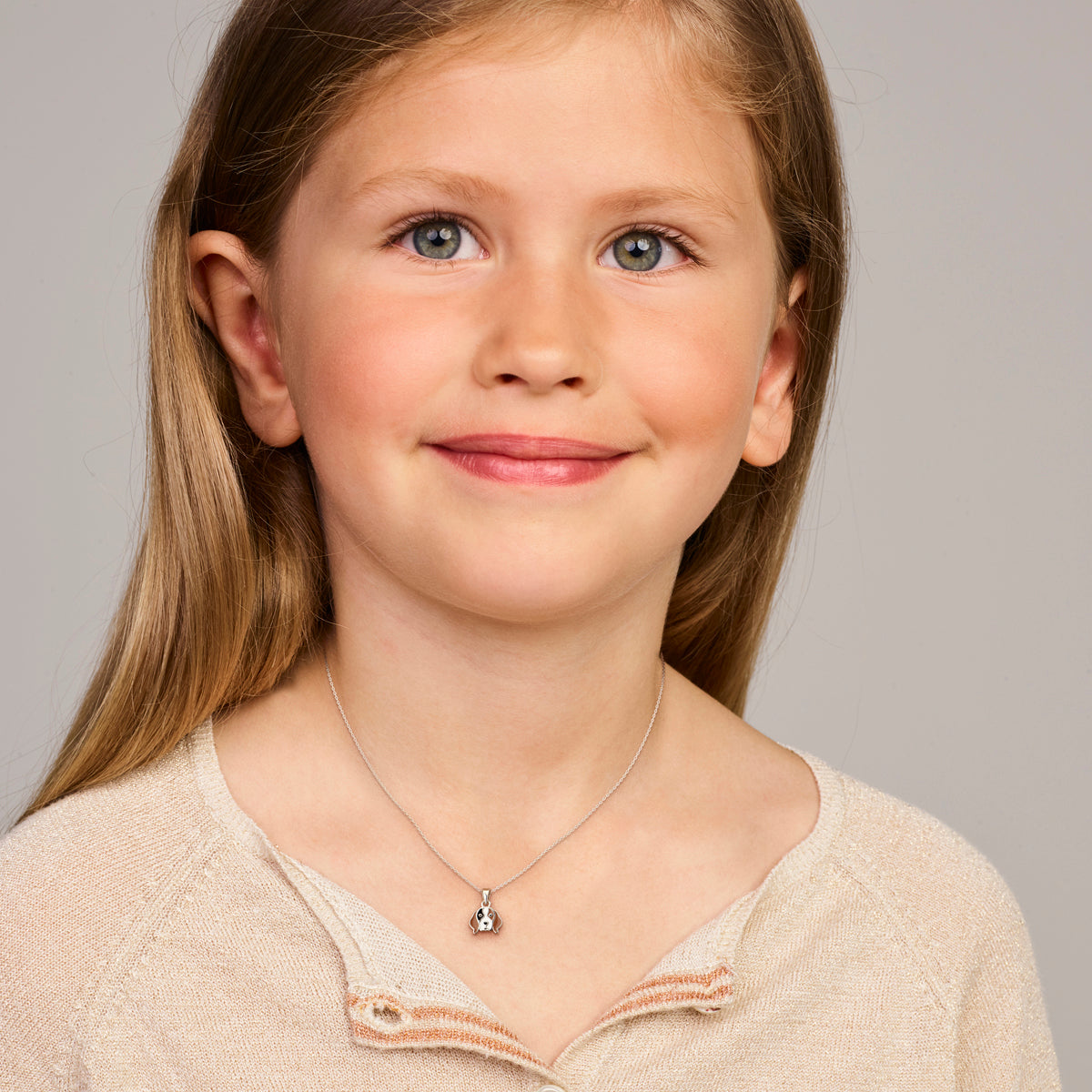 Een kindermodel draagt de zilveren kinderhanger Luna in de vorm van een hondje.