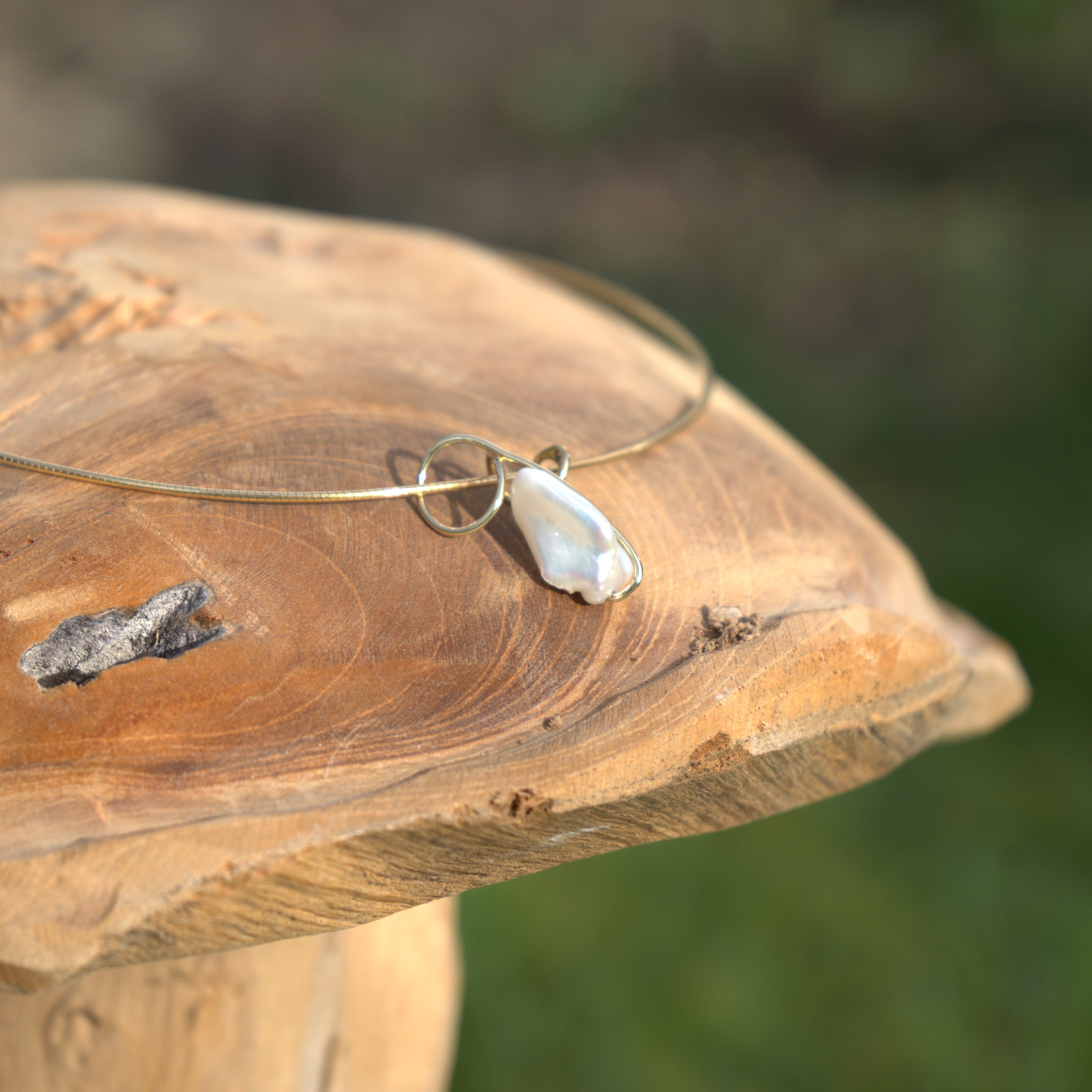 Een prachtige gouden hanger met edelsteen (parel), liefdevol gepresenteerd in een natuurlijke setting. Ontdek alle zilveren en gouden hangers bij Clary.