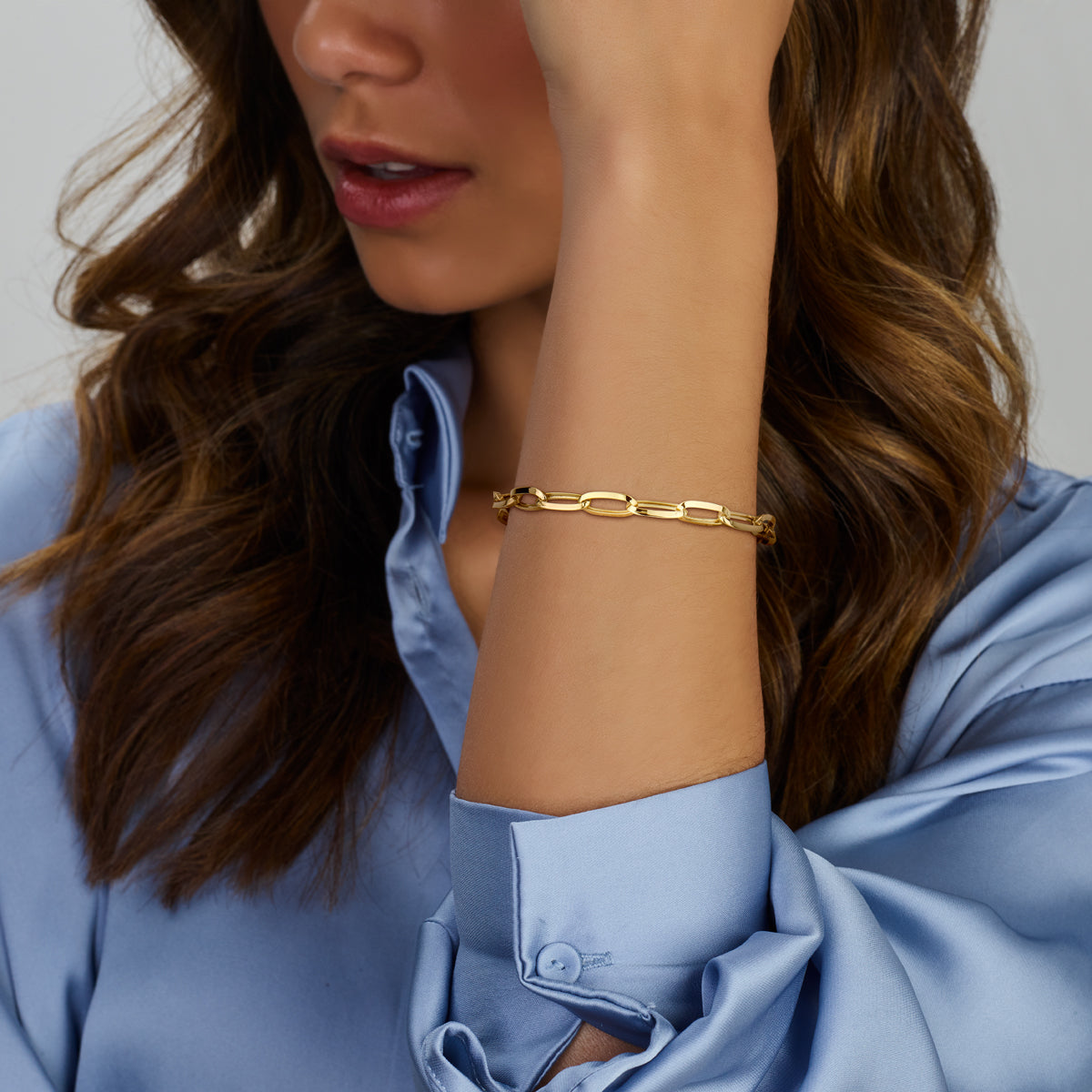 Model draagt de gouden paperclip armband van 14 karaat om de pols.