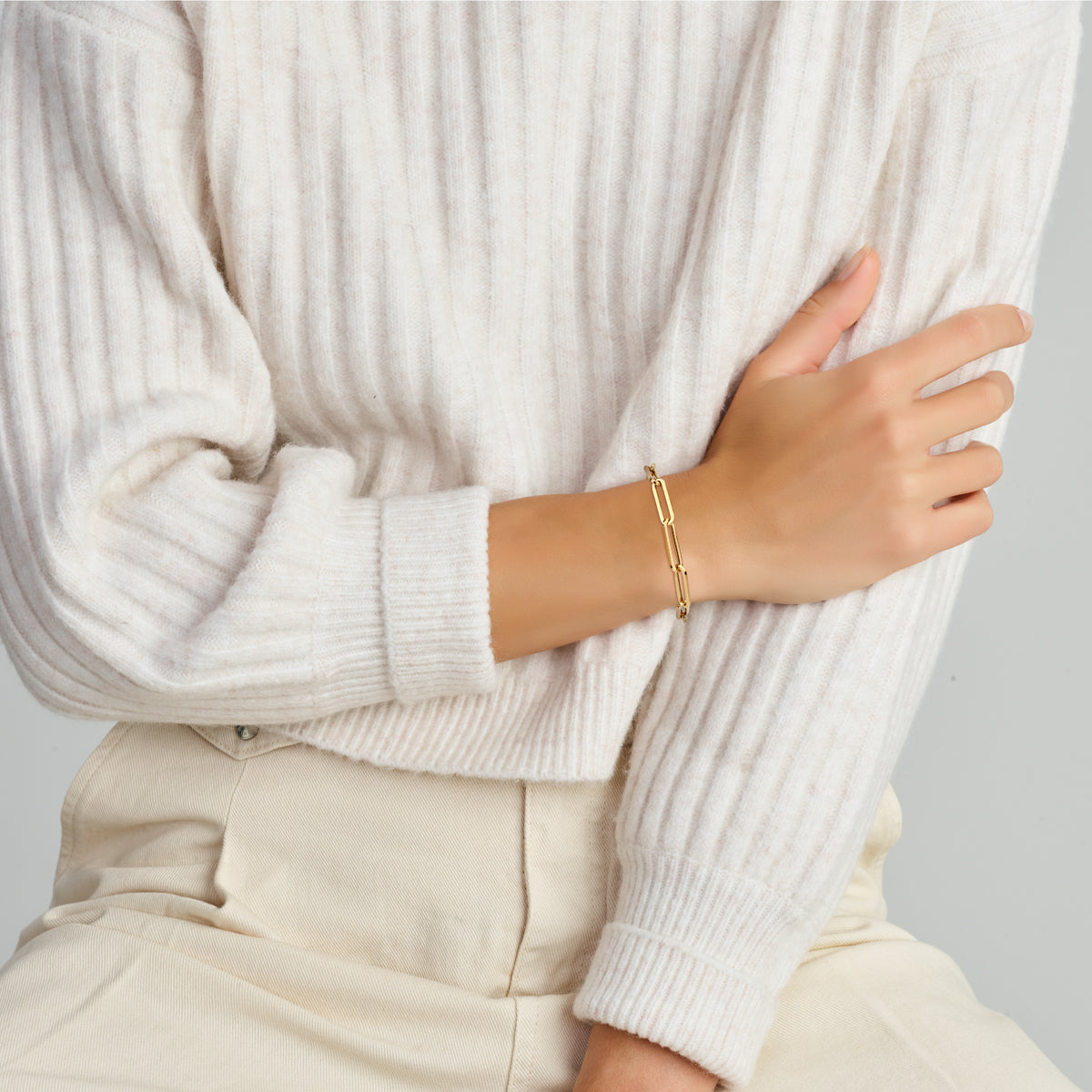 Model draagt de gouden paperclip armband van 14 karaat om de pols.