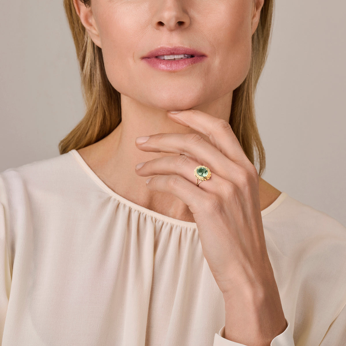 Model draagt de gouden ring met groene amethist van 14 karaat aan de hand.