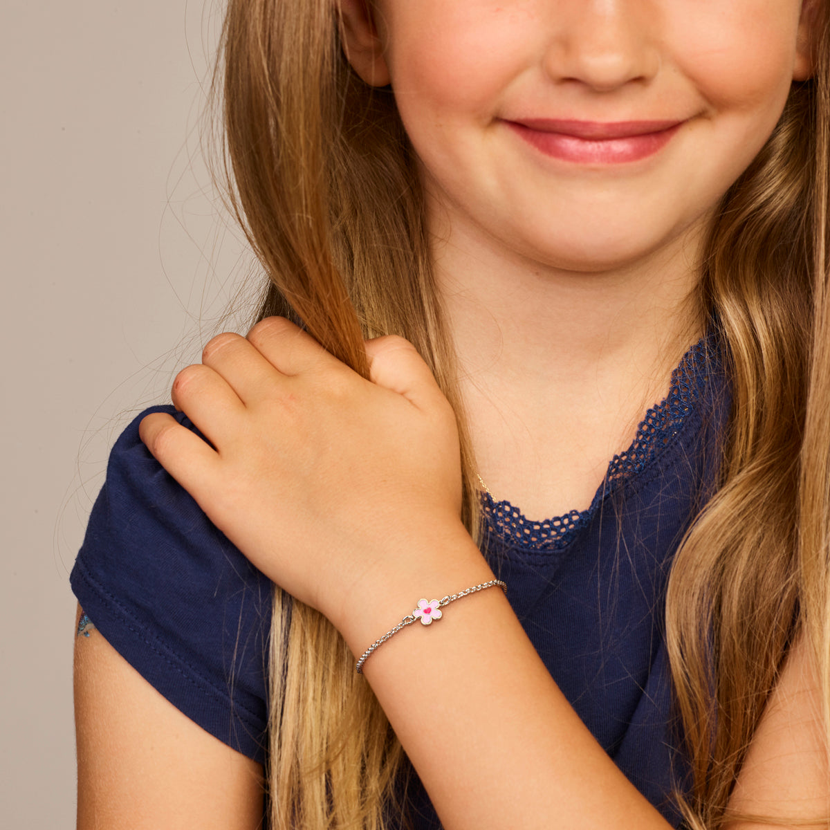 Model draagt de zilveren kinderarmband met bloem om de pols.