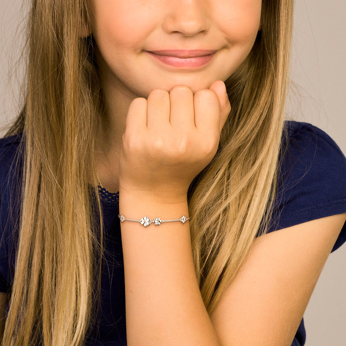 Model draagt de zilveren kinderarmband met bloemetjes om de pols.