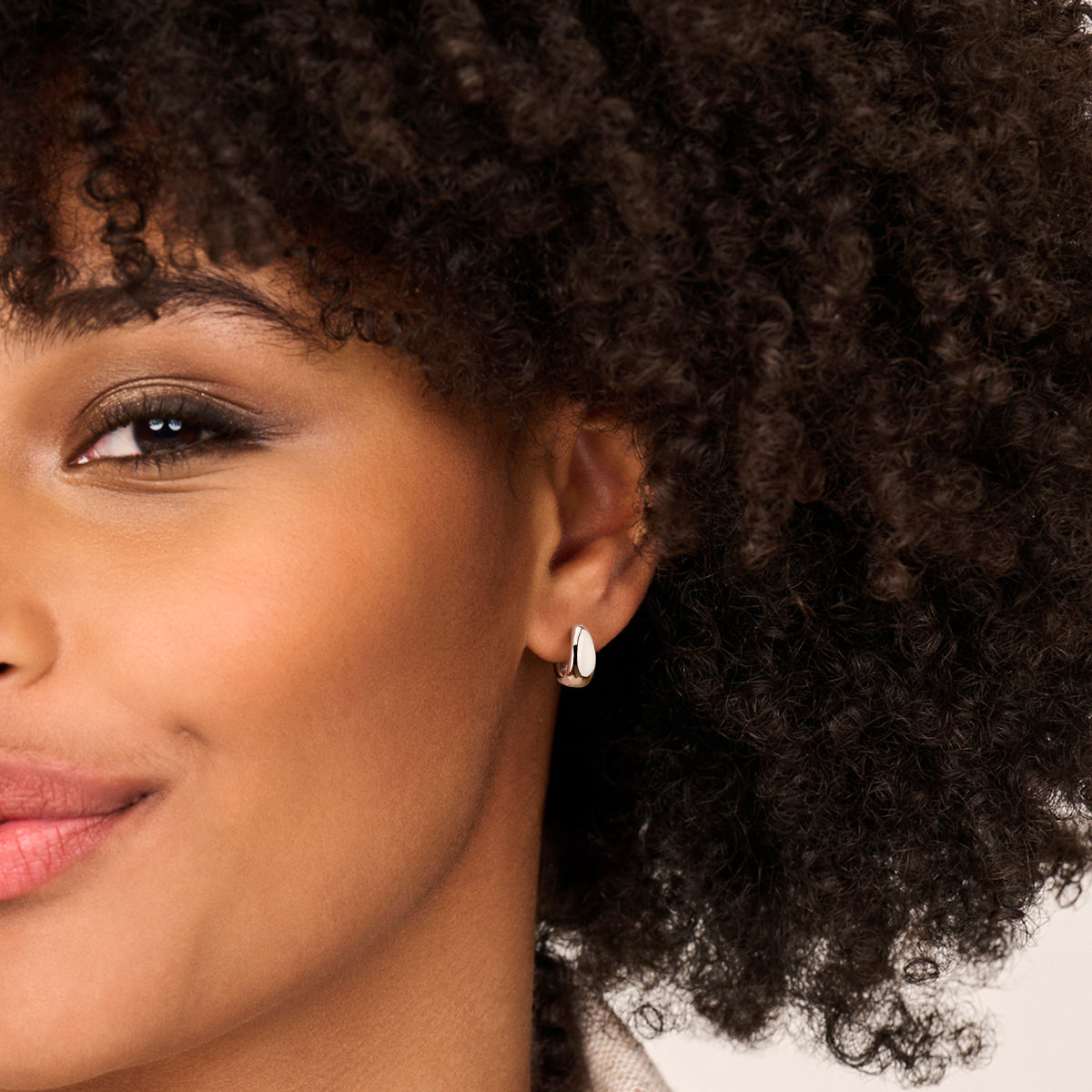 De opvallende 'Dyon' zilveren oorbellen van 13,5 mm breed gedragen in het oor.