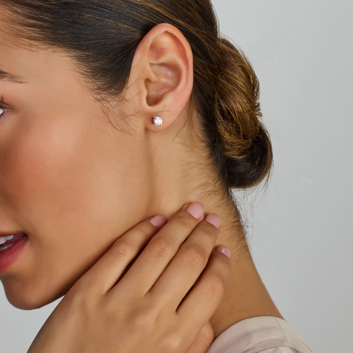 Zilveren 'Evie' oorknoppen van 4 mm gedragen door een model tonen een helder en stijlvol accent op het oor.