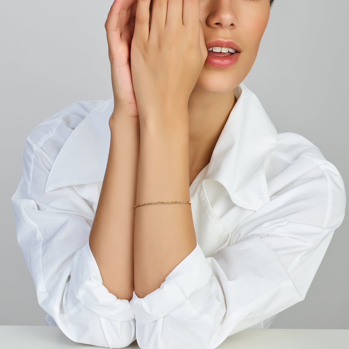 Een model draagt de 14k gouden 'Noa' armband, waarbij de fijne schakels zorgen voor een elegante en subtiele look.