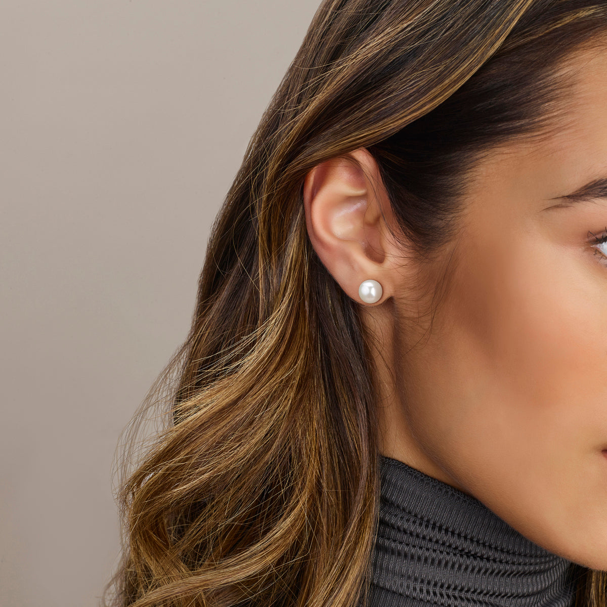 Een model draagt de 9 mm 'Claire' parel oorknoppen, die door hun grote formaat zorgen voor een chique statement look.