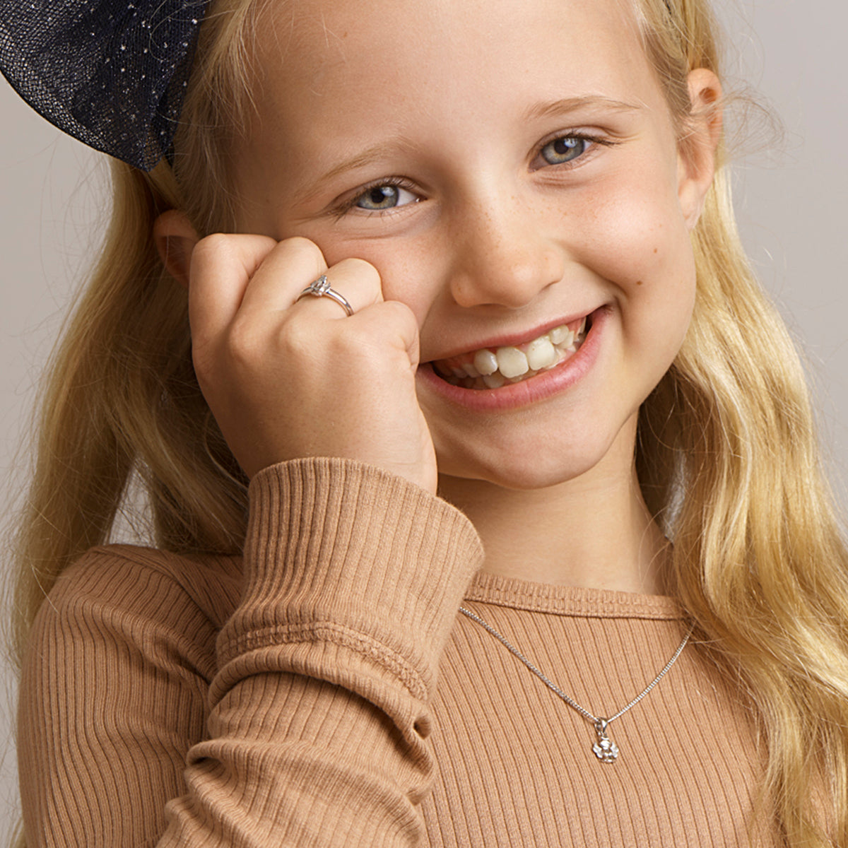 Een vrolijk kind model draagt de 'Sia' hanger om de grootte en lengte te tonen.