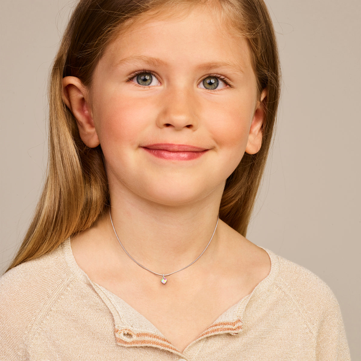 Een kindmodel draagt de 'Vola' hanger om de grootte en lengte te tonen.