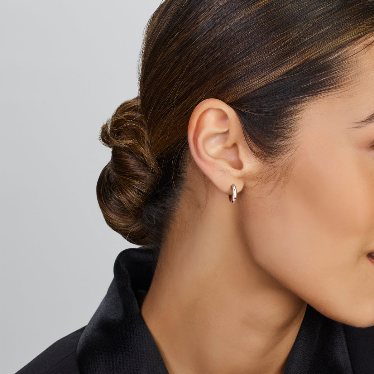 Een model draagt de subtiele 14 mm 'Vela' oorringen van zilver voor een tijdloze stijl.