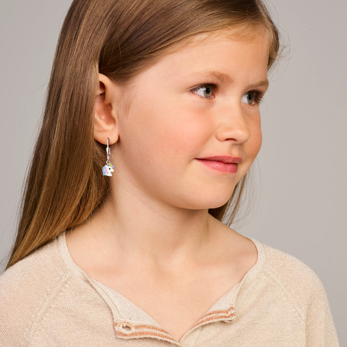 Een kindermodel draagt de zilveren oorhangers Fay met de eenhoorn.